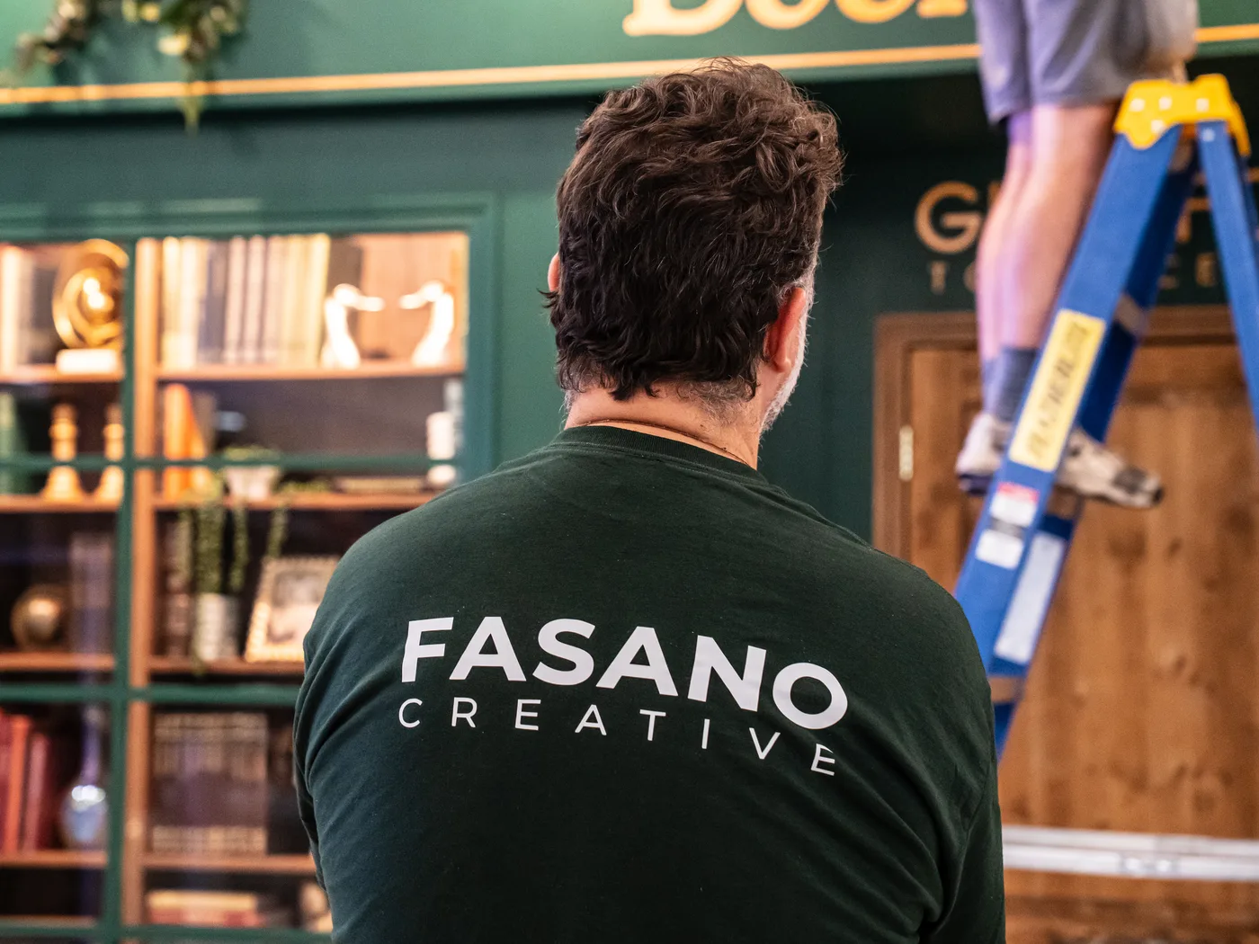 Roberto, from behind in a Fasano Creative shirt, overseeing the install of The Book Corner